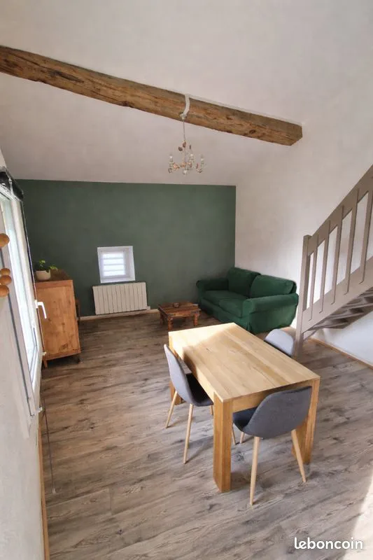 Salle à manger avec poutres apparentes et mur vert mousse