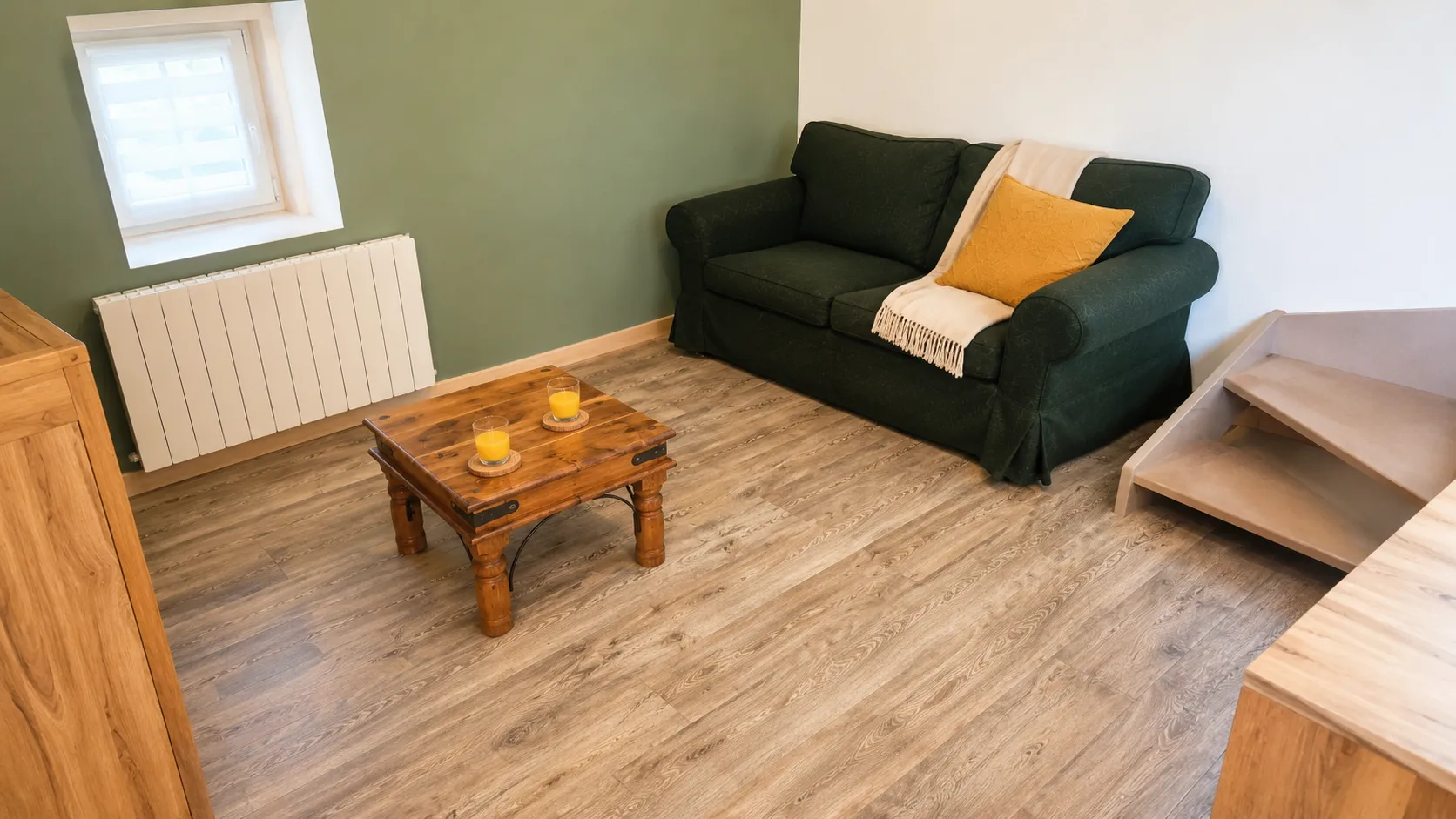 Coin salon avec canapé vert et table basse en bois