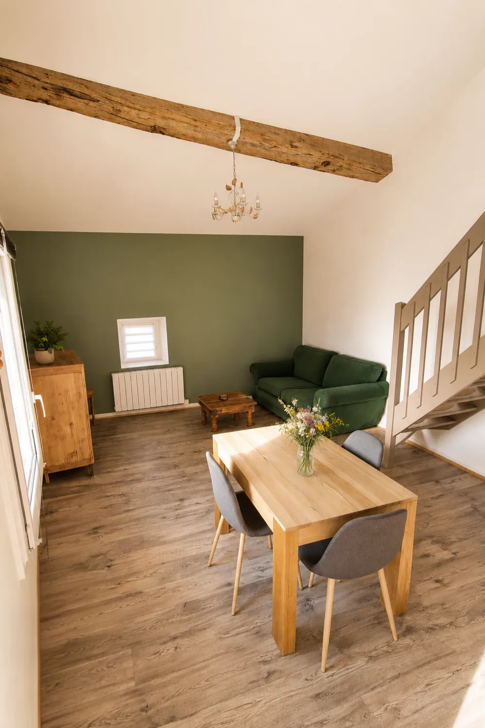 Salle à manger et coin salon, mur vert mousse et poutre apparente